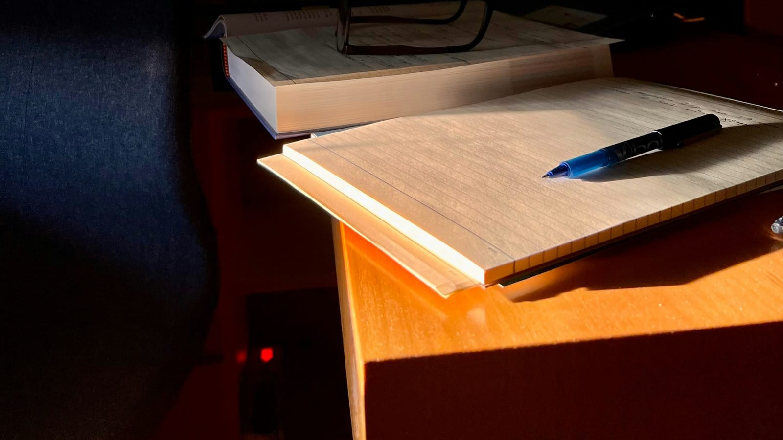 Pluma y libro sobre escritorio: detalle editorial del servicio de domicilio fiscal